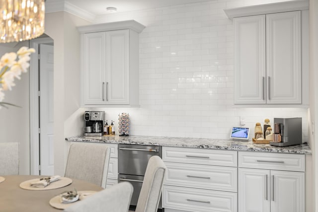 kitchen featuring white cabinetry, light stone counters, backsplash, and ornamental molding