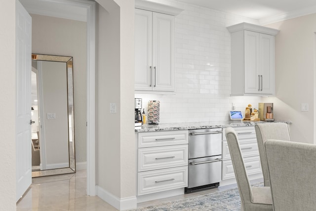 kitchen featuring light stone counters, backsplash, white cabinets, and ornamental molding