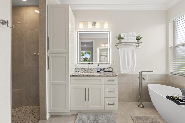 full bathroom with vanity, a wainscoted wall, a freestanding tub, ornamental molding, and tile walls