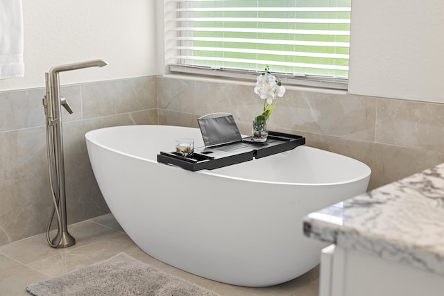 bathroom featuring tile patterned floors, tile walls, and a freestanding tub