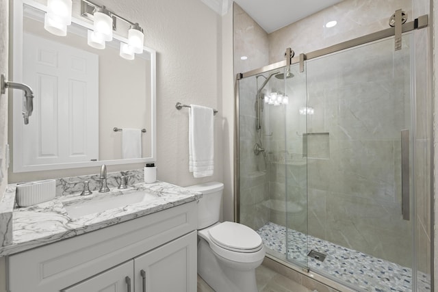 full bath with vanity, toilet, a textured wall, and a stall shower