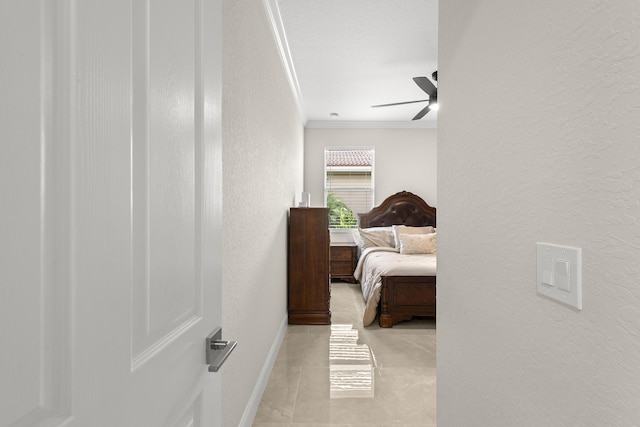 bedroom featuring baseboards, crown molding, a ceiling fan, and a textured wall