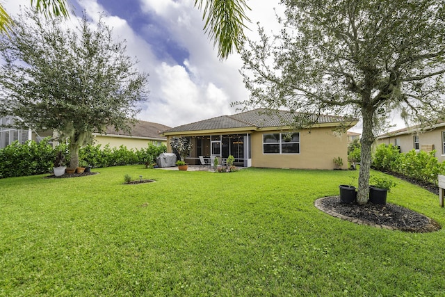 back of house with stucco siding, a tile roof, a yard, and a sunroom