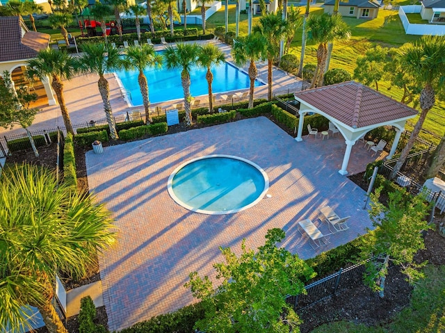 community pool with a gazebo, a community hot tub, and fence