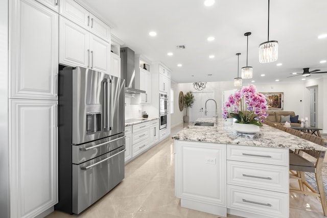 kitchen with a sink, stainless steel appliances, white cabinetry, wall chimney exhaust hood, and open floor plan