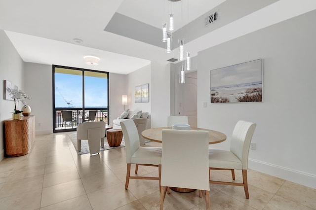 dining area featuring light tile patterned floors, baseboards, expansive windows, and visible vents