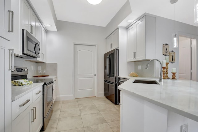 kitchen featuring light tile patterned floors, light stone counters, a sink, appliances with stainless steel finishes, and tasteful backsplash