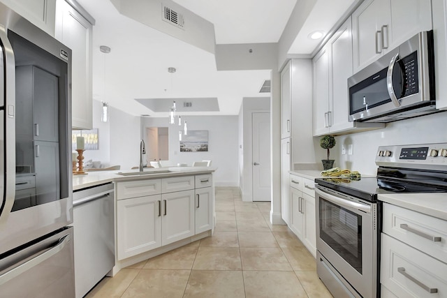 kitchen with stainless steel appliances, light countertops, visible vents, a sink, and a peninsula