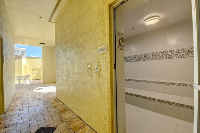 bathroom featuring brick floor, a textured wall, and a sauna