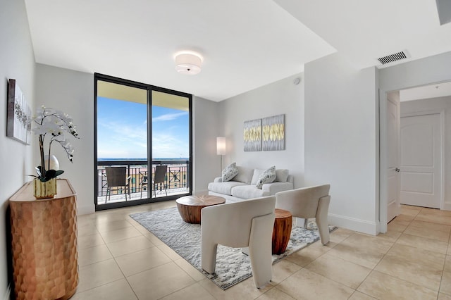 living room with a wall of windows, visible vents, baseboards, and light tile patterned floors