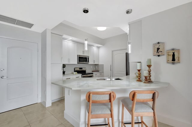 kitchen with visible vents, a breakfast bar area, a peninsula, stainless steel appliances, and a sink