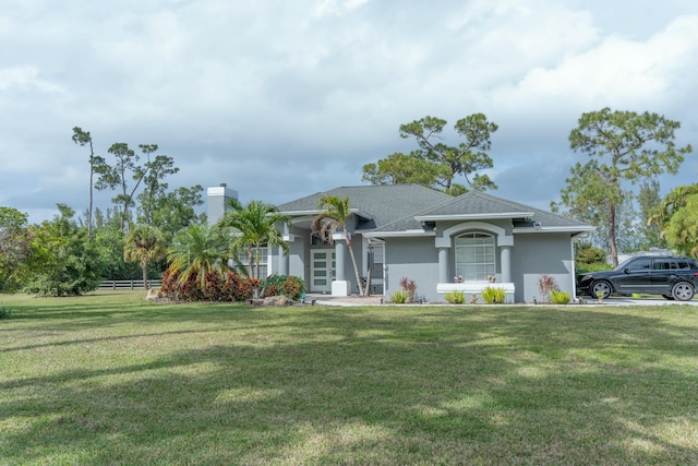 view of front of home with a front yard, fence, a chimney, and stucco siding