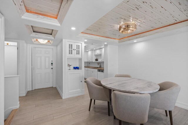 dining area with ornamental molding, light wood-type flooring, a raised ceiling, and wooden ceiling