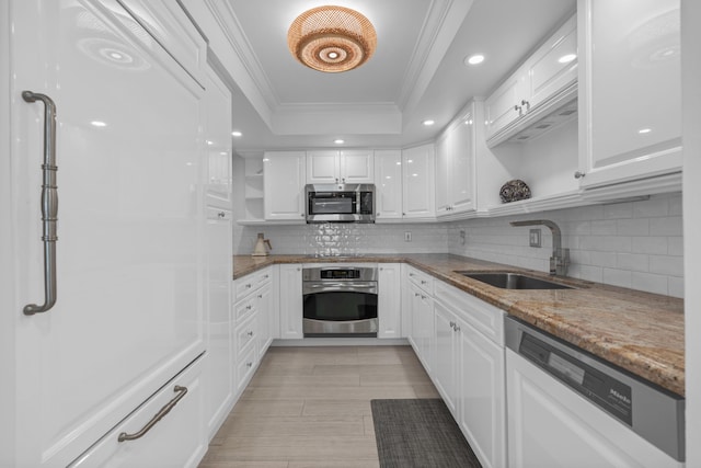 kitchen featuring a tray ceiling, crown molding, open shelves, stainless steel appliances, and a sink