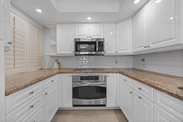 kitchen with light stone counters, recessed lighting, stainless steel appliances, white cabinetry, and backsplash