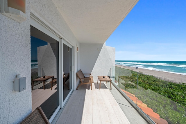 balcony with a water view, a beach view, and a wall mounted AC