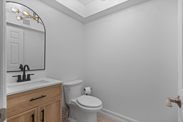 bathroom with visible vents, baseboards, toilet, wood finished floors, and vanity