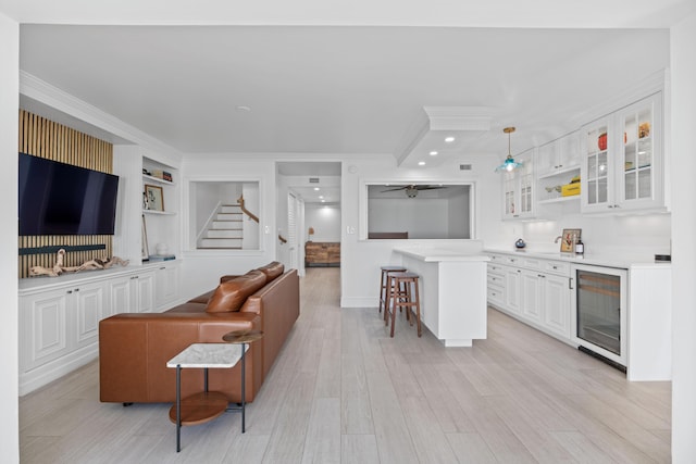 living room with wine cooler, crown molding, recessed lighting, stairway, and light wood-style flooring