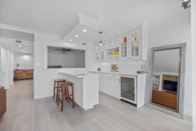 kitchen with beverage cooler, white cabinets, glass insert cabinets, a breakfast bar, and hanging light fixtures