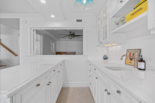 interior space with a sink, visible vents, light countertops, glass insert cabinets, and crown molding