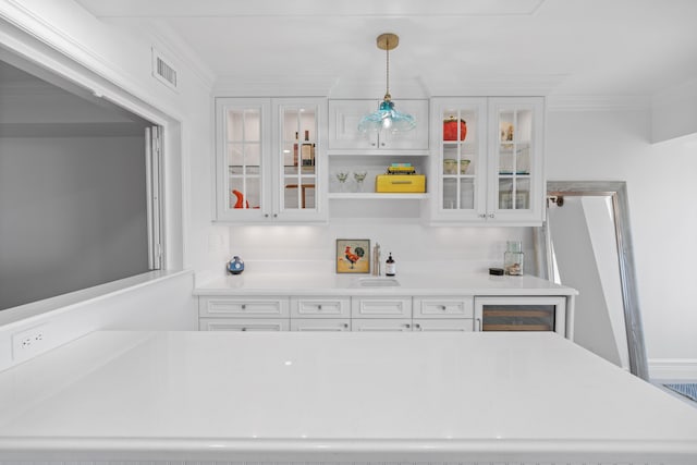 kitchen with white cabinets, crown molding, and light countertops