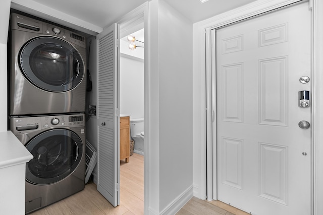 laundry area featuring stacked washer and clothes dryer, light wood-style flooring, and laundry area