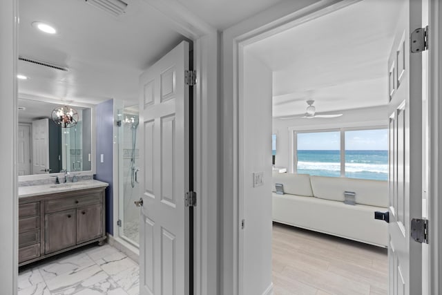 full bathroom with visible vents, a water view, ceiling fan, a shower stall, and vanity