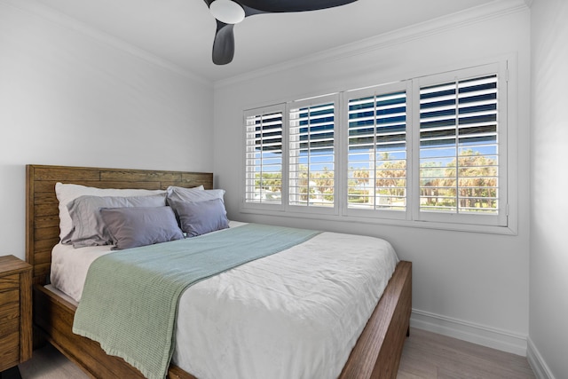 bedroom with multiple windows, crown molding, baseboards, and wood finished floors