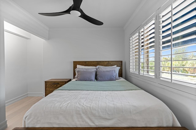 bedroom featuring baseboards, light wood-style flooring, a ceiling fan, and crown molding