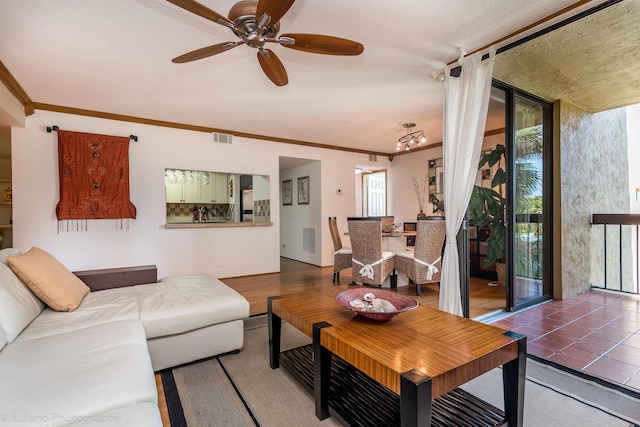 living room with ceiling fan, tile patterned flooring, visible vents, and crown molding