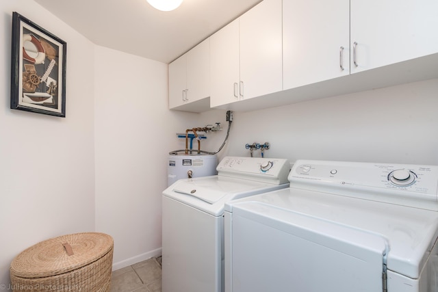 washroom featuring baseboards, washer and clothes dryer, cabinet space, water heater, and light tile patterned floors