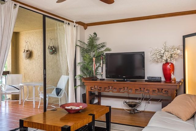 living area with ornamental molding and a ceiling fan