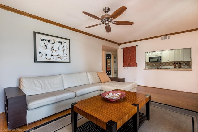 living room featuring crown molding, a ceiling fan, wood finished floors, and visible vents