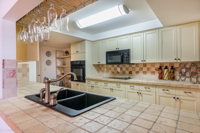 kitchen with decorative backsplash, a sink, and black appliances