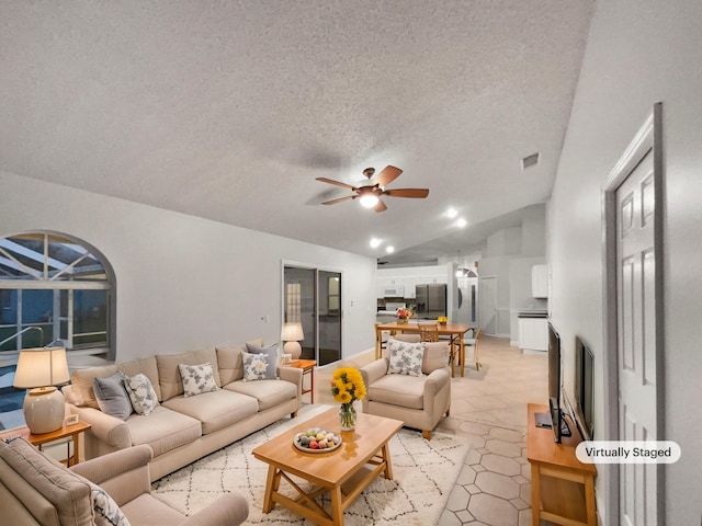 living area featuring visible vents, light tile patterned flooring, ceiling fan, vaulted ceiling, and a textured ceiling