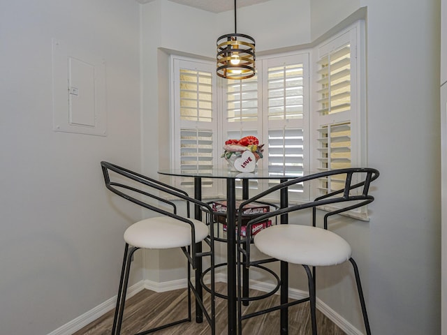 dining area with wood finished floors, electric panel, and baseboards