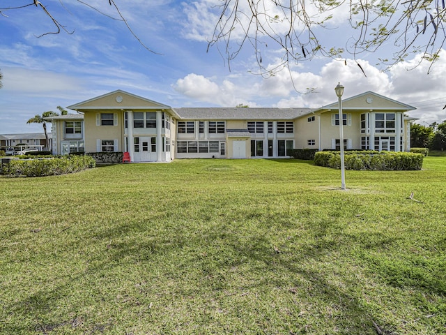 back of property with a lawn and stucco siding