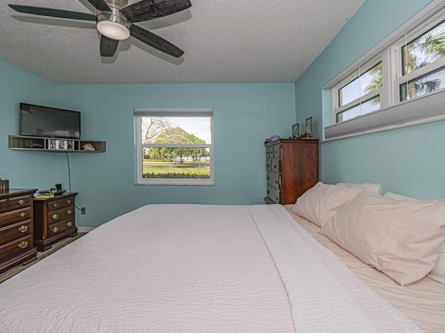 bedroom with multiple windows, a ceiling fan, and a textured ceiling