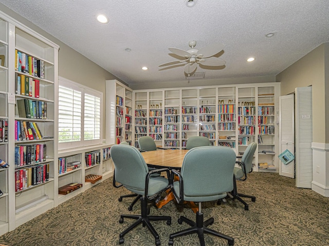 carpeted office featuring bookshelves, a textured ceiling, and recessed lighting