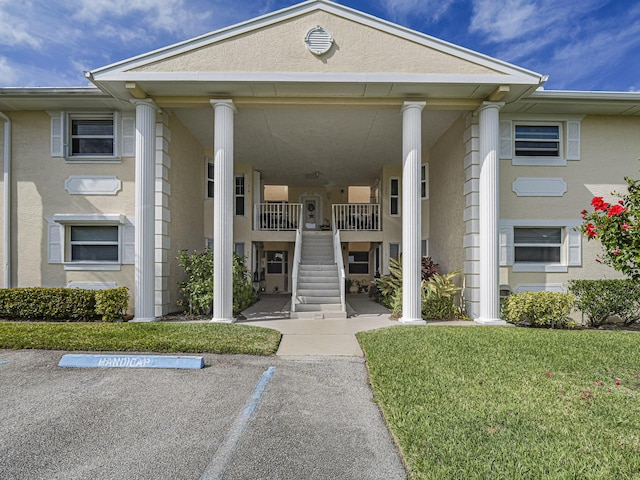 property entrance with uncovered parking, a lawn, and stucco siding