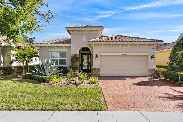 mediterranean / spanish house with a garage, stone siding, decorative driveway, stucco siding, and a front lawn