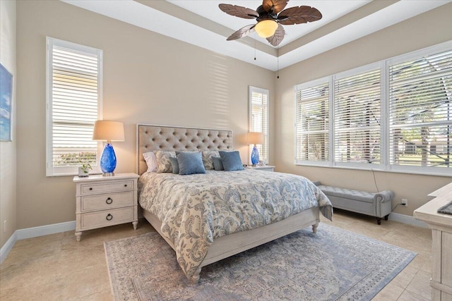 bedroom featuring baseboards, a raised ceiling, a ceiling fan, and light tile patterned flooring