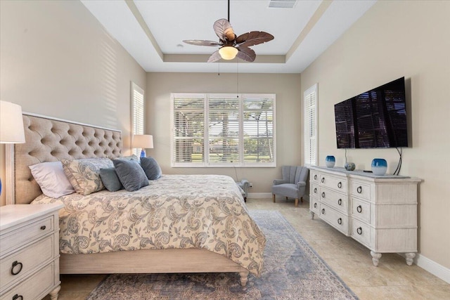 bedroom featuring light tile patterned floors, ceiling fan, a raised ceiling, and baseboards