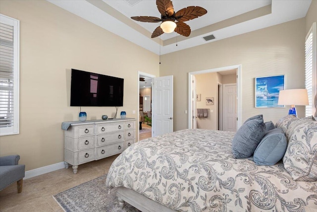 bedroom with light tile patterned floors, a raised ceiling, visible vents, a ceiling fan, and baseboards