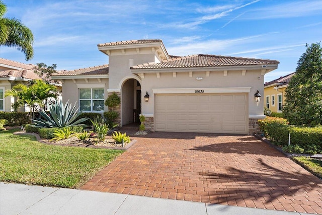 mediterranean / spanish house with decorative driveway, stucco siding, a garage, stone siding, and a tiled roof