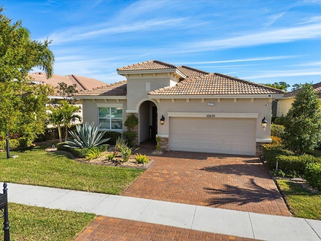 mediterranean / spanish house with a garage, stone siding, decorative driveway, a front lawn, and stucco siding