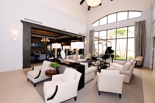 tiled living area with baseboards, a high ceiling, visible vents, and ceiling fan with notable chandelier