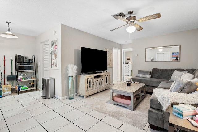 living area featuring visible vents, a ceiling fan, a textured ceiling, light tile patterned floors, and baseboards