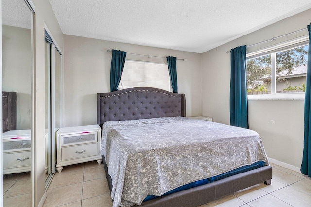 tiled bedroom with a closet, baseboards, and a textured ceiling