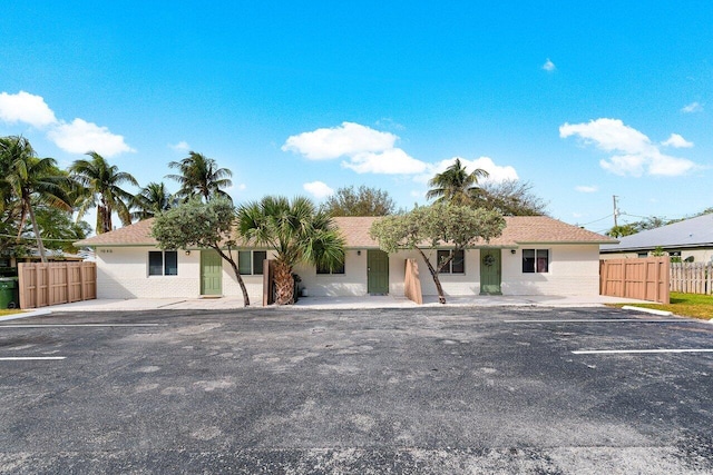 view of front of home with uncovered parking and fence